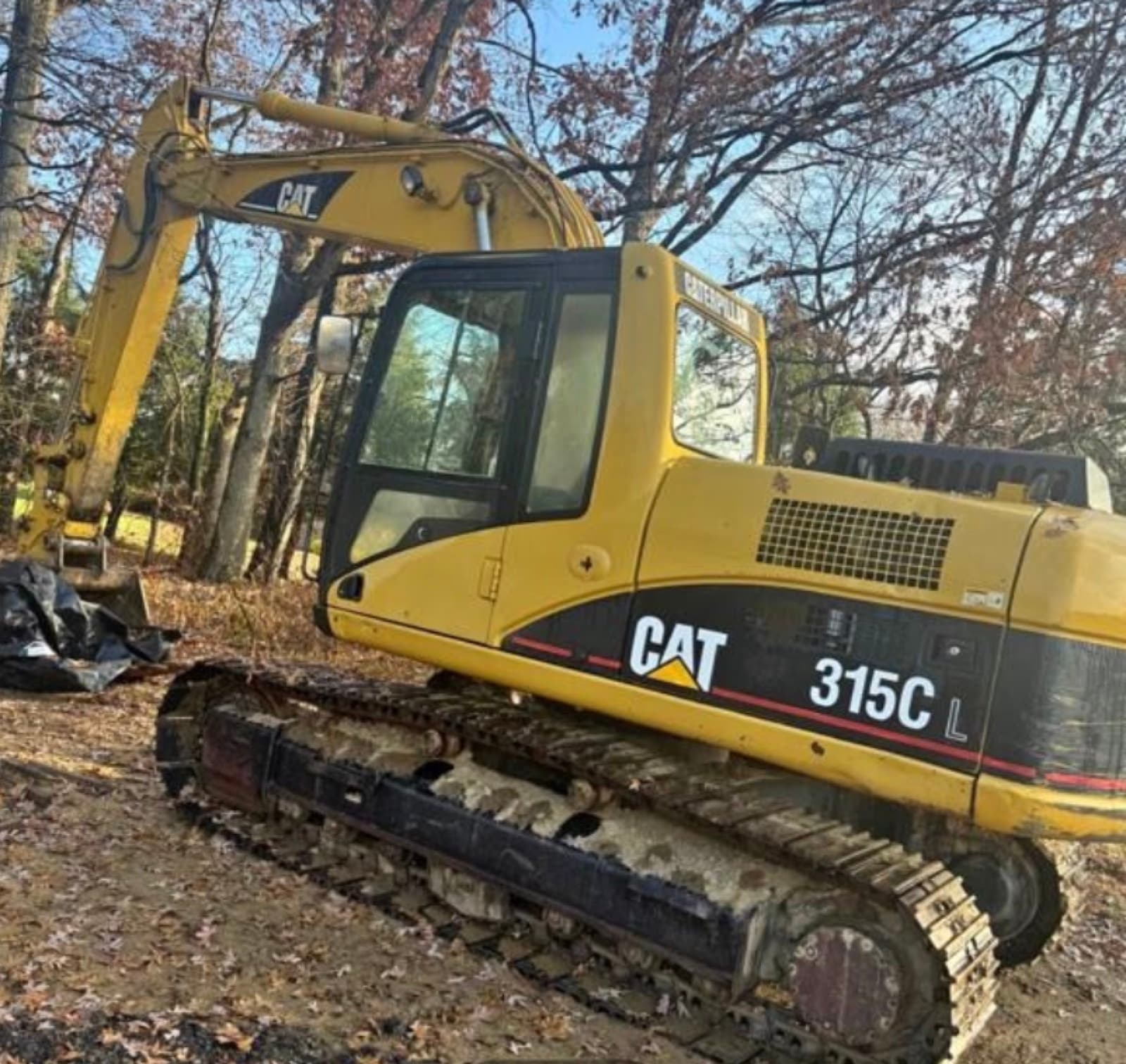 Long reach Caterpillar 312D excavator positioned beside a concrete drain along a highway in Guyana.